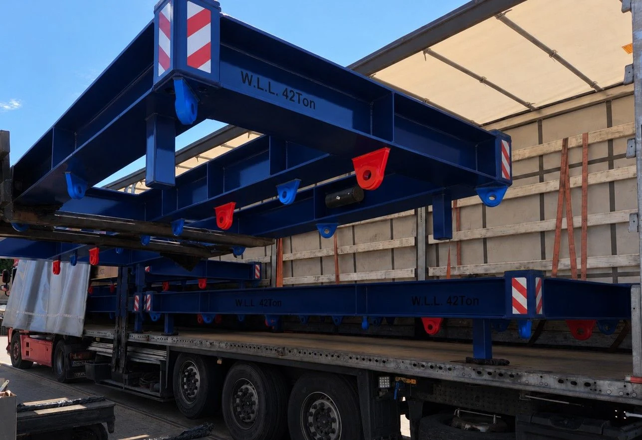 Blue painted steel frames being loaded onto a curtain-side truck